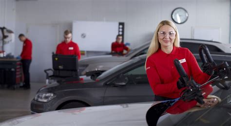 Serviso darbuotojai keičia automobilio stiklą