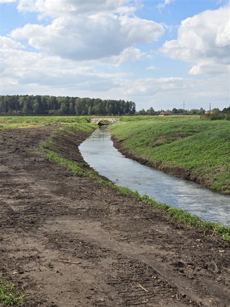 Upės krantas su kelio atitvarais ir apverstu automobiliu