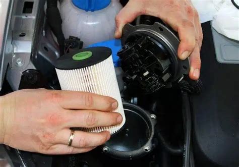 Serviso mechanikas keičia kuro filtrą BMW automobilyje