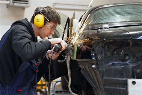 Darbuotojas, dėvintis saugos priemones automobilių remonto dirbtuvėse