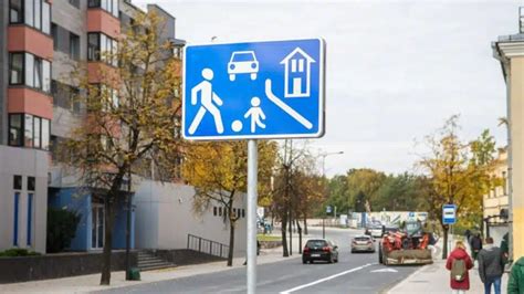 Simbolinė iliustracija, vaizduojanti kelio ženklus, šviesoforus ir autonominį automobilį.