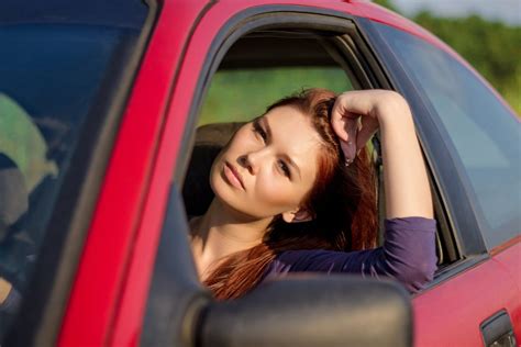Žmogus, sėdintis prie automobilio vairo ir šypsosi