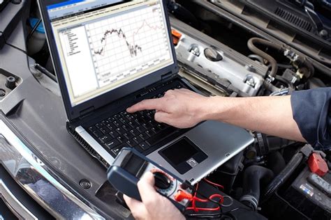 Mechanikas atlieka automobilio diagnostiką su kompiuterine įranga