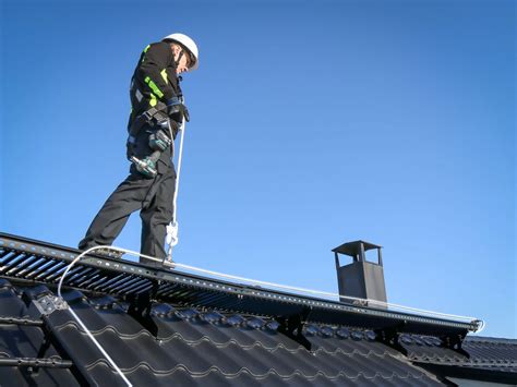 Darbininkas su saugos diržu ant stogo