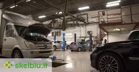 Autoserviso meistras tikrina automobilio žibintą