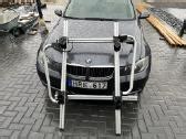 BMW automobilis su stogo skersiniais ir dviračių laikikliais
