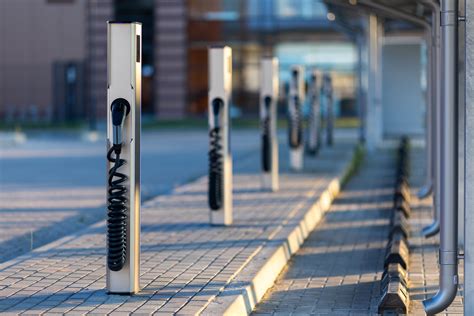 Vaizdas ateities automobilių stovėjimo aikštelės su elektromobilių įkrovimo stotelėmis ir želdynais