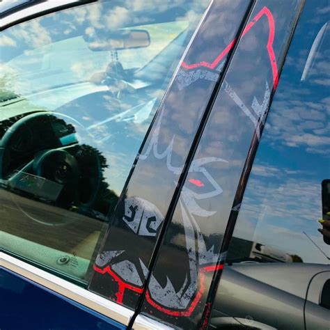 Nuotrauka su automobilio durelių statramsčiu, kurioje matomas lipdukas su rekomenduojamu padangų slėgiu