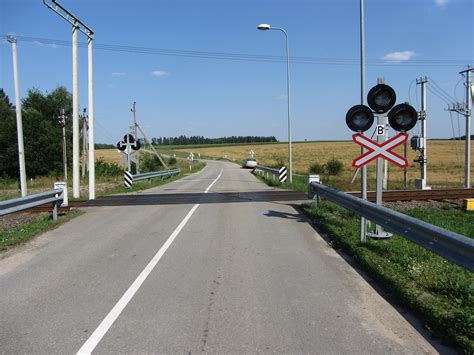 schematiškas geležinkelio pervažos vaizdas su šviesoforu ir kelio ženklais