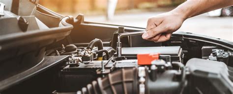 Autoserviso darbuotojas keičia automobilio akumuliatorių