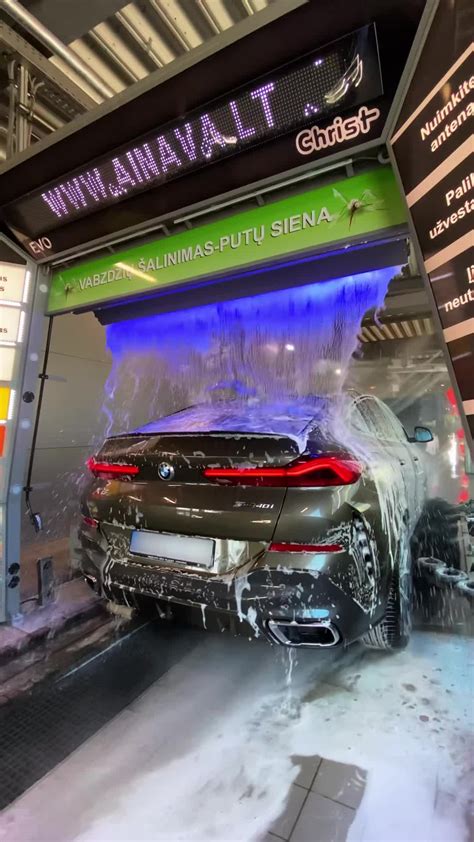 Rankinės automobilių plovyklos specialistai, kruopščiai plaunantys automobilį