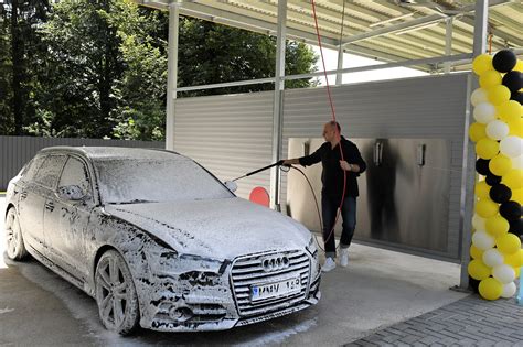 Žmogus, plaunantis automobilį savitarnos plovykloje