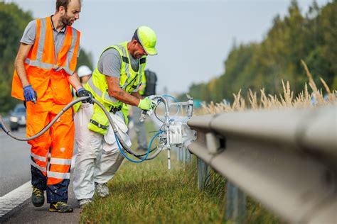 Nuotrauka su kelio priežiūros darbuotojais, naudojant modernią techniką.